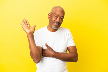 Cuban Senior isolated on yellow background holding copyspace imaginary on the palm to insert an ad