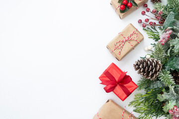 Christmas decoration with gift boxes, styled fir branche, pine cones, garland on white background. Top view with copy space.