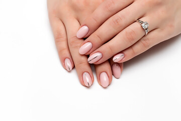 Nude, beige, natural manicure with a silver strip on long oval nails close-up on a white background. A beautiful ring, decoration.	