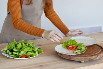 young girl in an apron makes a healthy salad of vegetables and herbs in her kitchen