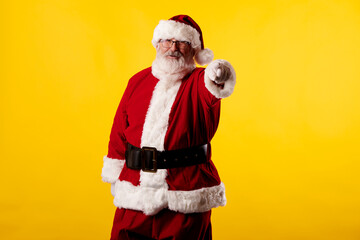 Santa Claus pointing his finger at the camera on yellow background