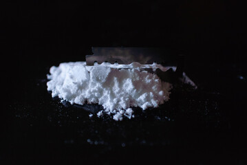 Razor Blade on drug powder on reflection black background.Copy space.