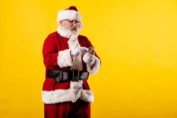 Santa Claus using a mobile phone on yellow background