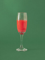 red liquid in champagne glas against green background. Retro minimalism. creative abstract art.
