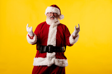 Fototapeta na wymiar Santa Claus making a rocker gesture on yellow background
