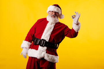 Fototapeta na wymiar Santa Claus making the OK gesture on yellow background