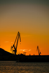Vertical view of port shipyard cranes against sunset sky, Ferrol, Galicia, Spain
