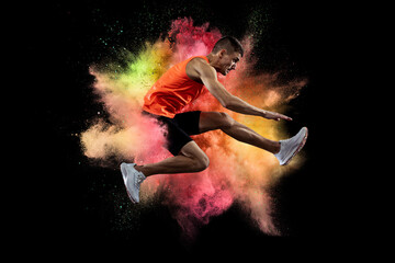 Creative collage of young man, professional athlete, runner training isolated over colorful powder explosion on black background. Flyer