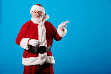Fototapeta na wymiar Santa Claus pointing his finger at billboard on blue background
