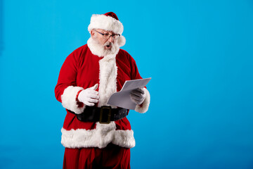 Fototapeta na wymiar Santa Claus reading a letter on blue background