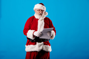 Fototapeta na wymiar Santa Claus reading a letter on blue background