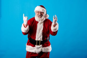 Fototapeta na wymiar Santa Claus making a rocker gesture on a blue background