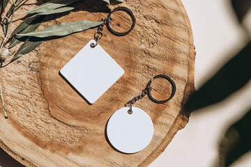 Keychain mockup among olive leaves to display design. Blank white sublimation key chain photo.