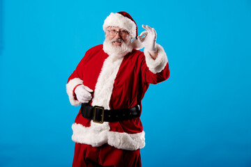 Fototapeta na wymiar Santa Claus making OK gesture on blue background