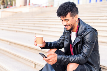 young latin student smiles consulting his phone