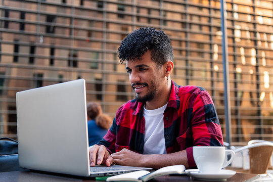 latin man working with his computer on a terrace