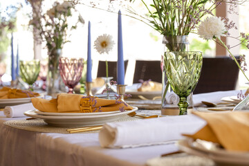The festive table is served with plates with napkins, glasses and knives and candles