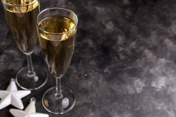 Two champagne glasses and Christmas ornaments on a black background. New year party concept