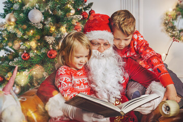 Fototapeta na wymiar reading a book with santa claus - children and santa concept