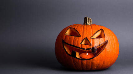 Halloween pumpkin or jack-o-lantern with glowing eyes on a gray background. Halloween pumpkin with copyspace on gray background.