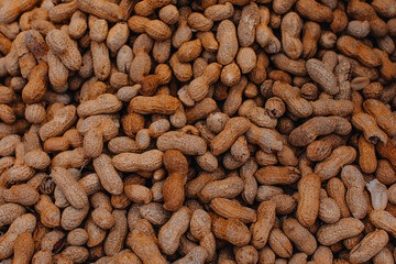 Natural beige background from unpeeled peanuts. Healthy and organic food. Nuts