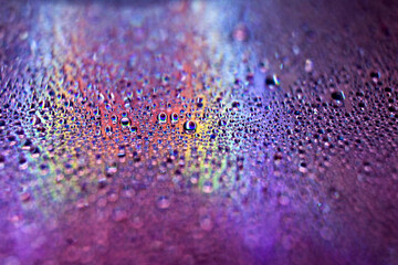 Selective focus shot of colorful reflective water drops on a digital disc surface