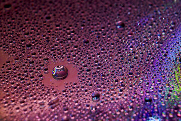 Selective focus shot of colorful reflective water drops on a digital disc surface