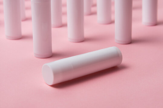Lot of white plastic lip gloss tubes on pink background
