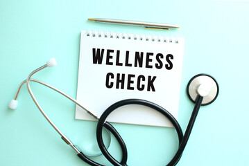 White notepad with the words WELLNESS CHECK and a stethoscope on a blue background.