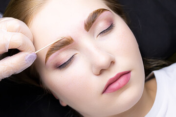 the face of a blonde model who is lying on the couch in a white T-shirt, with paint applied on her...