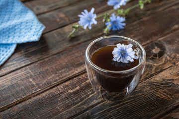 Chicory drink in transparent thermo glass cup with fresh flowers