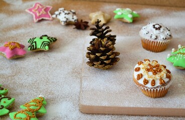Christmas composition: cookies in the shape of a Christmas tree, gingerbread man, bells and colorful stars decorated on a background of powdered sugar and wood