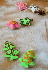 Christmas composition: cookies in the shape of a Christmas tree, gingerbread man, bells and colorful stars decorated on a background of powdered sugar and wood