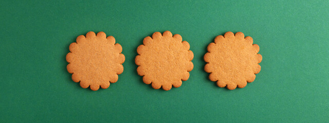 Round gingerbread cookies isolated on green background, top view. Banner for website, template with...