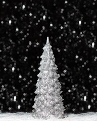 Christmas decorations view of silver tree on dark background with silver colors bokeh and artificial snow. Holidays concept with copy space at the top