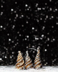 Christmas decorations view of three wooden tree colored in solver glitter at the tips and white hedgehog on dark background with silver colors bokeh and artificial snow. Holidays concept copy space