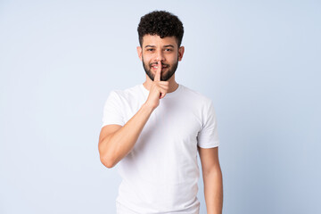 Young Moroccan man isolated on blue background showing a sign of silence gesture putting finger in...