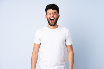 Obraz premium Young Moroccan man isolated on blue background shouting to the front with mouth wide open