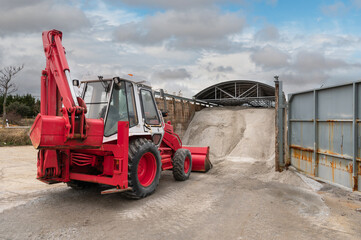 Excavator loading salt for road treatment in winter