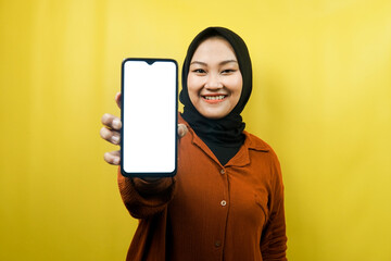 Beautiful young asian muslim woman holding smartphone with white or blank screen, promoting app, promoting something, isolated, advertising concept