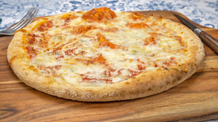 Pizza italienne fraîche entière avec des tomates sur une planche de bois
