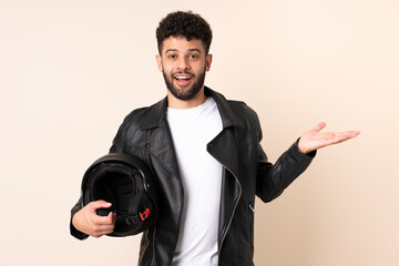 Young Moroccan man with a motorcycle helmet isolated on beige background with surprise facial expression