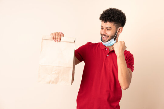 Young man holding a takeaway food bag ___ celebrating a victory