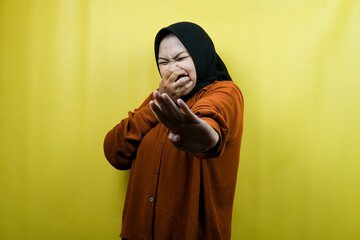 Beautiful young asian muslim woman with hand covering mouth, refusing something isolated