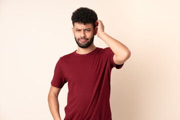 Young Moroccan man isolated on beige background having doubts