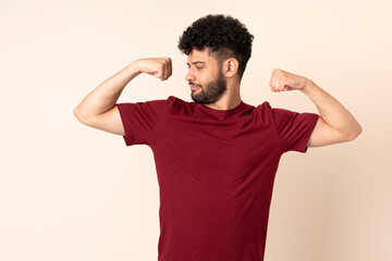 Young Moroccan man isolated on beige background doing strong gesture