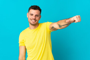 Young caucasian handsome man isolated on blue background giving a thumbs up gesture