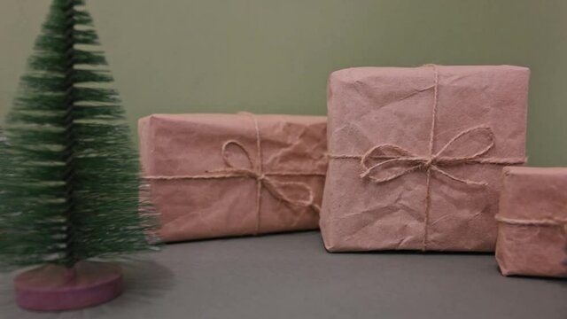 Celebratory Christmas and New Year's holidays background. Gift boxes wrapped craft paper with twine , recycling present on green background 