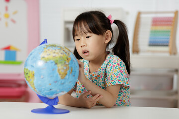 young girl learning world globe at home
