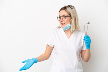 Dentist caucasian woman holding tools isolated on white background with surprise expression while looking side